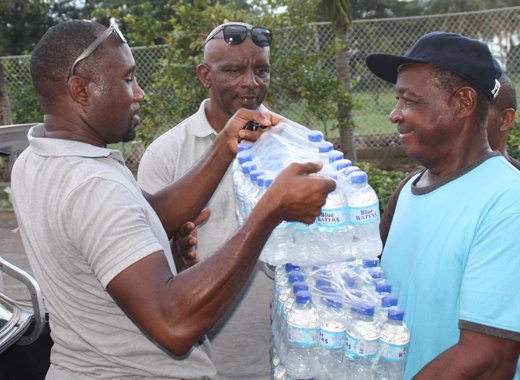 Chance, left, and Prescott, get some assistance in transporting the cases of water into the emergency shelter. (IWN photo)