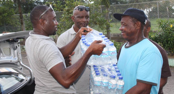 Chance, left, and Prescott, get some assistance in transporting the cases of water into the emergency shelter. (IWN photo)
