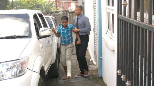 A police officer escorts Baptiste to a police vehicle outside the Serious Offences court on Monday.