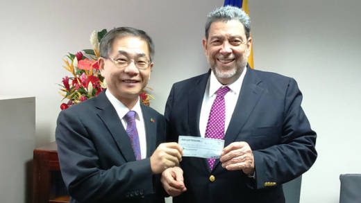 Ambassafor Ger, left, presents the cheque to Prime Minister Gonsalves.