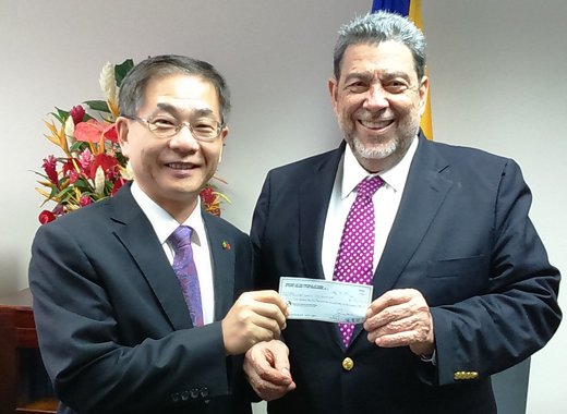 Ambassafor Ger, left, presents the cheque to Prime Minister Gonsalves.