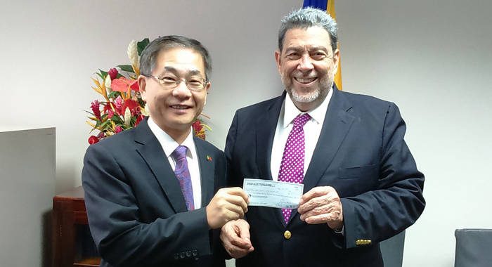 Ambassafor Ger, left, presents the cheque to Prime Minister Gonsalves.