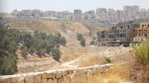 Many Palestinian labourers from the Shuafat refugee camp across the barrier work on construction in the Israeli settlement Pisgat Zeev in East Jerusalem to the right. Credit: Jillian Kestler-DAmours/IPS.