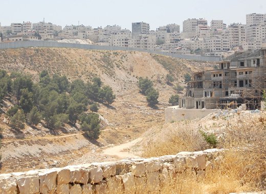 Many Palestinian labourers from the Shuafat refugee camp across the barrier work on construction in the Israeli settlement Pisgat Zeev in East Jerusalem to the right. Credit: Jillian Kestler-DAmours/IPS.