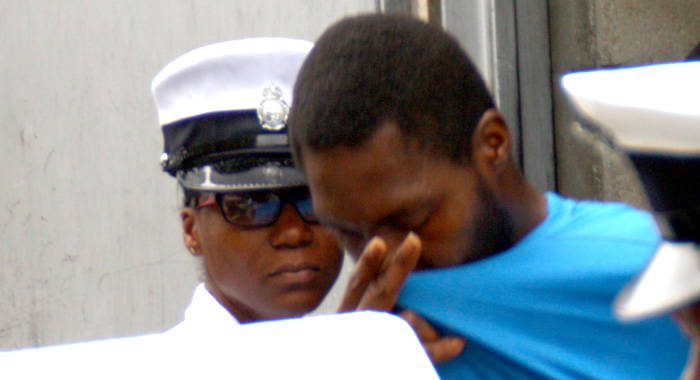 Keon Scott attempts to hide his face as he is led away from the Serious Offences Court on Tuesday. 
