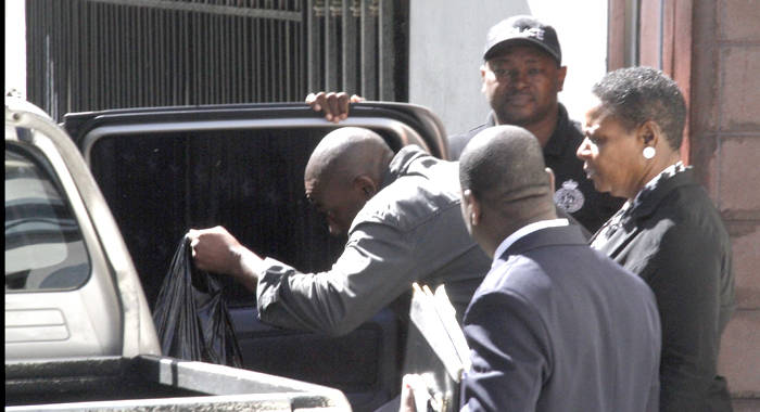 Junior Jarvis quickly enters a police vehicle after exiting the Serious Offences Court on Thursday. (iWN photo)