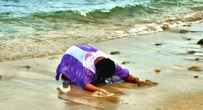 In this undated The Garifuna Heritage Foundation Inc. photo, a Garifuna woman prostrates herself and wails on the sea shore at Balliceaux.