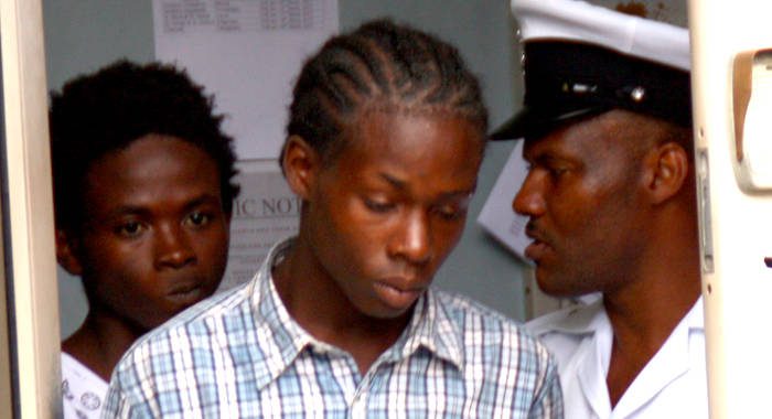 A police officer escorts Osbourne Rogers, left and Atibon Campbell from the Kingstown Magistrate's Court on Monday. 
