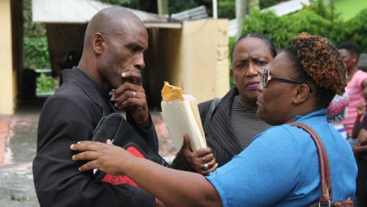 Lawyer Kay Bacchus-Baptiste, centre, looks on as her client, Pastor Nigel Morgan, speaks with a woman outside the Mesopotamia Magistrate's court on Friday. (iWN photo)