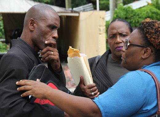 Lawyer Kay Bacchus-Baptiste, centre, looks on as her client, Pastor Nigel Morgan, speaks with a woman outside the Mesopotamia Magistrate's court on Friday. (iWN photo)