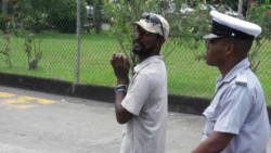 A police officer escorts a handcuffed Otis Lockhart from the wharf to the Central Police Station. 