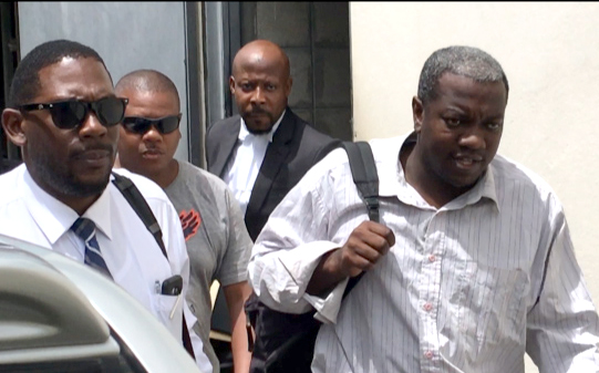 Charles, right, accompanied by Duncan, left, another detective, and his lawyer, leaves the court on Monday. (iWN photo)