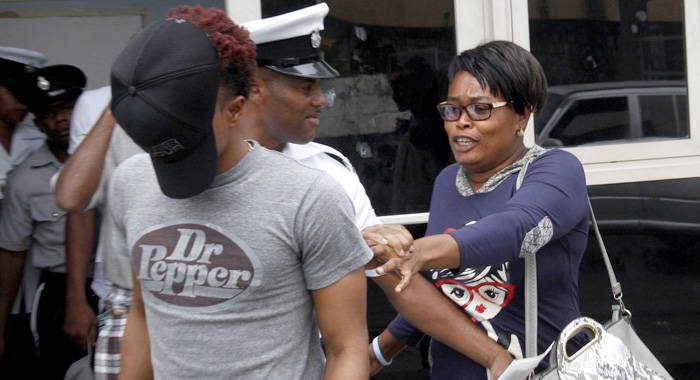Rosia John, right, seen here in an August 2017 photo as she urged her son, Enrique John, to hide his face after a sex charge, has been charged with murdering one of her son’s relatives, one day after her son was murdered in Kingstown on Friday, April  11, 2026. 