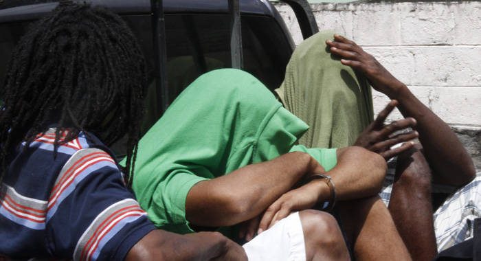 The accused men use their clothing to hide their faces as they are transported to prison. (iWN photo)