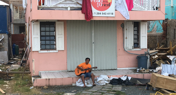 A Filipino expat plays his guitar in Road Town amidst debris in the aftermath of hurricane Irma. CMC photo