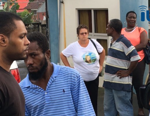 Inether Bailey-Holder, background centre, and other person look as Primus, left, who is accused of killing her daughter, is led back to prison on Friday. (iWN photo)