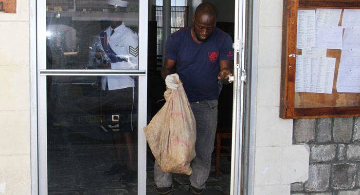 A police officer removes from the High Court on Dec. 12, 2017 the bag from which a package of cocaine is missing. (iWN photo)