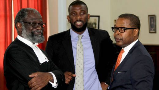 Lead counsel for the petitioners, Queen's Counsel Stanley "Stalky" John, left, chats with petitioner Ben Exeter, left, and counsel Akin John, centre after Wednesday's court hearing. (iWN photo)