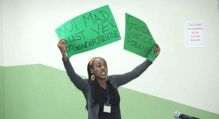 Lecturer in political science at the Cave Hill Campus, Dr. Kristina Hinds, holds up a placard during Gonsalves' lecture in Barbados on Feb. 22. (Photo: Barbados TODAY)
