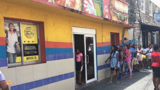 Persons queue up outside Western Union in Kingstown on Saturday. (iWN photo) 