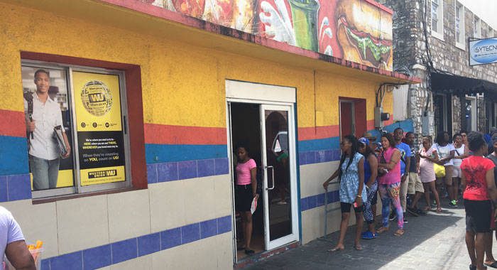 Persons queue up outside Western Union in Kingstown on Saturday. (iWN photo) 