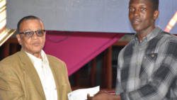 Junior Sportsman of the Year 2017, Dillon Douglas receives a check from McGregory Sealey of the National Lotteries Authority. (Photo: NLA of SVG/Facebook)