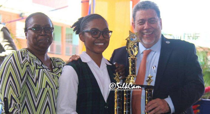 Iana Ferguson, flanked by her mother, receives her award from Prime Minister Ralph Gonsalves. (Photo: Silkcam Services/Facebook)