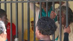 A dectective monitors interaction between Althia Morgan and her son at the holding cell at their court on Monday. Chrystal Morgan, standing to the left of her mother in the cell, will also spend four years in jail. (iWN Photo)