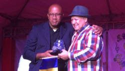 Pastor Fidel Taylor, right, receives a plaque from Danroy Ballantyne of the National Gospel Fest Committee. (iWN photo)