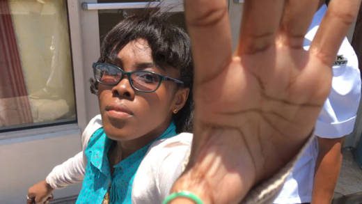 Krystal Morgan grabs at iWitness News' recording devices as police officers (not pictured) escort her to jail in April 2018. (iWN photo) 