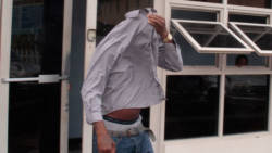 The defendant, Orlando Lowman uses his shirt to hide his face as he leaves the Kingstown Magistrate's Court. (iWN photo)