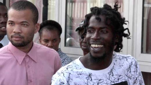 Abdul Garrick, right, greets persons as police escort him to court on Monday. (iWN photo)