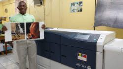 Government Printer, Richard Ollivierre demonstrates the quality of the printing by the newly-installed industrial high-speed colour printer.