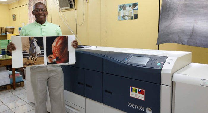 Government Printer, Richard Ollivierre demonstrates the quality of the printing by the newly-installed industrial high-speed colour printer.