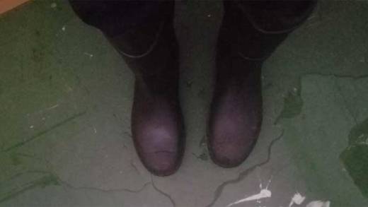A staff member wears a pair of winter boots while standing in a pool of water inside the main Kingstown Anglican School building on Thursday. 