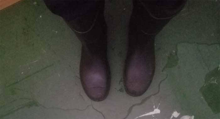 A staff member wears a pair of winter boots while standing in a pool of water inside the main Kingstown Anglican School building on Thursday. 