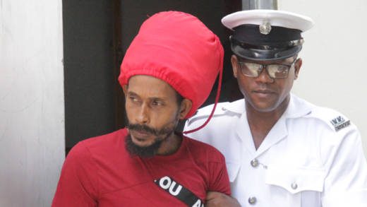 A police officer escorts Hezekiah Naphtali from the Serious Offences Court on Nov. 28, when he was sent for psychiatric evaluation. The Mental Health Centre says he is not fit to plead in the case. (iWN photo) 