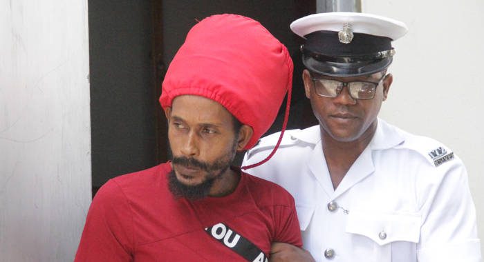 A police officer escorts Hezekiah Naphtali from the Serious Offences Court on Nov. 28, when he was sent for psychiatric evaluation. The Mental Health Centre says he is not fit to plead in the case. (iWN photo) 