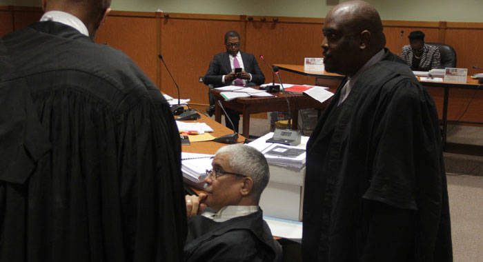 Petitioner Benjamin Exeter, in background, is framed by lead counsel for the government, Douglas Mendes, centre, and Kenny Kentish, during a break in Tuesday's proceedings. (iWN photo)