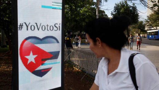 A woman passes by a screen displaying images promoting the vote for "yes" for the constitutional referendum, in Havana, Cuba, Feb. 5, 2019. (REUTERS/Stringer)