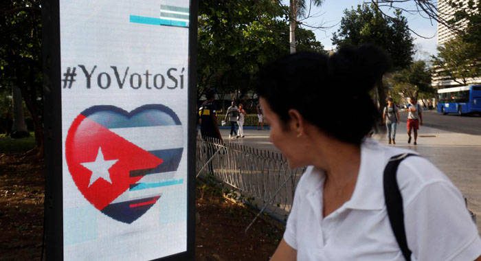 A woman passes by a screen displaying images promoting the vote for "yes" for the constitutional referendum, in Havana, Cuba, Feb. 5, 2019. (REUTERS/Stringer)