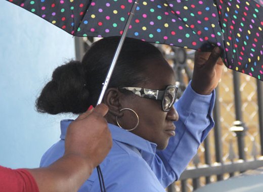 Julia Phillips uses and umbrella to try to hide herself as she leaves the Kingstown Magistrate's Court on Wednesday. (iWN photo)