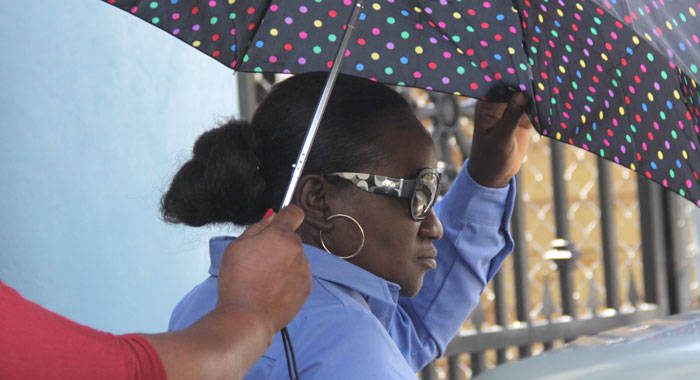 Julia Phillips uses and umbrella to try to hide herself as she leaves the Kingstown Magistrate's Court on Wednesday. (iWN photo)