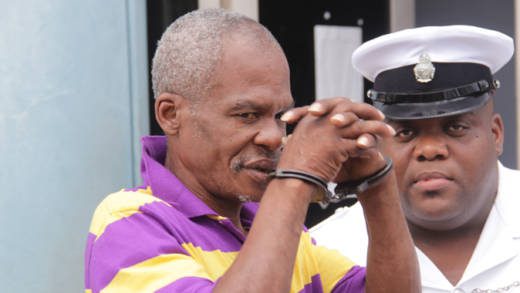 Woman beater Bertram Wright attempts to hide his face from journalists as he leaves the Kingstown Magistrate's Court on Monday. (iWN photo)