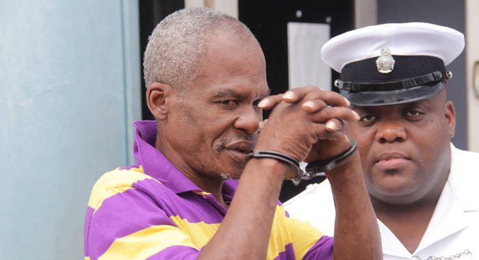 Woman beater Bertram Wright attempts to hide his face from journalists as he leaves the Kingstown Magistrate's Court on Monday. (iWN photo)