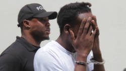 Murder accused, Etson Time, hides his face as he is escorted from court on Monday. (iWN photo)