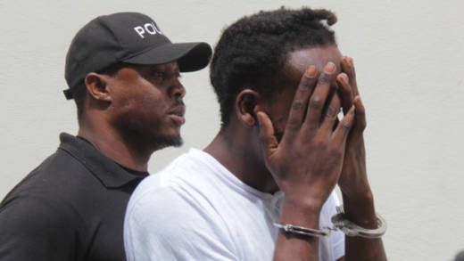 Murder accused, Etson Time, hides his face as he is escorted from court on Monday. (iWN photo)