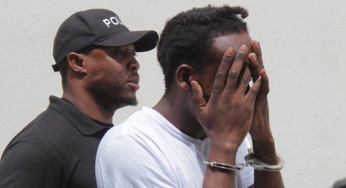 Murder accused, Etson Time, hides his face as he is escorted from court on Monday. (iWN photo)