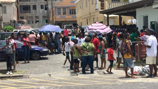 Persons who worked on the road cleaning programme wait to be paid in Kingstown on Monday. (iWN photo)