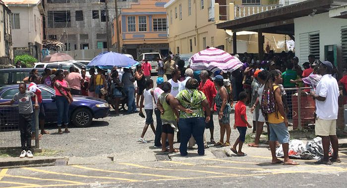 Persons who worked on the road cleaning programme wait to be paid in Kingstown on Monday. (iWN photo)